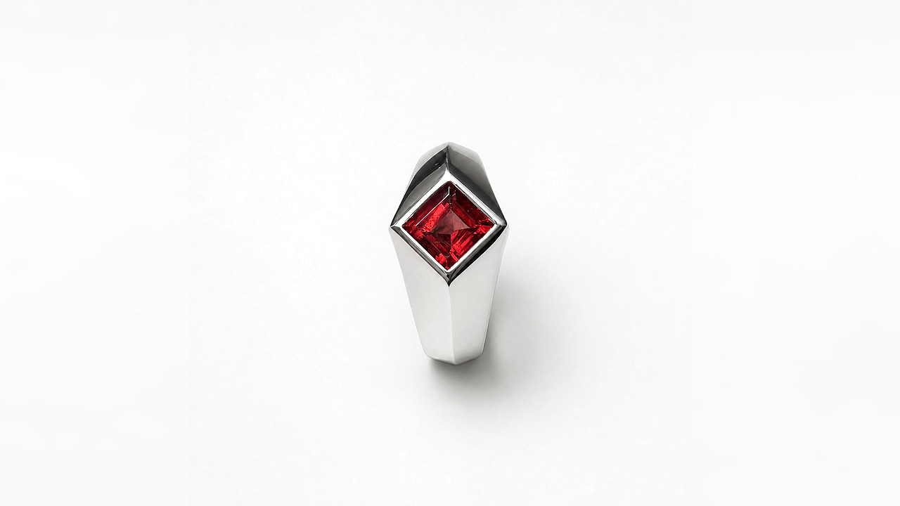 Top view of the ring head: the red garnet sits on point between faceted silver planes.